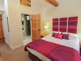 A bedroom with a bed and mirrored bathroom at The Old Grainstore Bolton Low Houses near Wigton