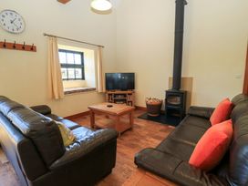 A living room with two black leather sofas a wooden coffee table a television and a wood burning stove at The Old Stables in Winterborne Stickland
