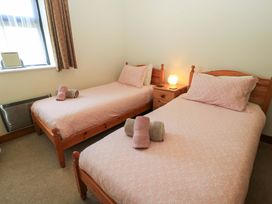 A bedroom with two single wooden beds with pink bedspreads and rolled towels on top with a nightstand and lamp between the beds at The Old Stables in Winterborne Stickland