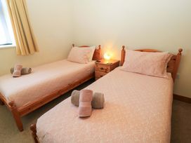 A bedroom with two single beds with pink patterned bedding and towels on them with a wooden nightstand and lamp between the beds at The Old Stables in Winterborne Stickland