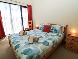 A bedroom with a bed with blue patterned bedding two bedside tables with lamps a wooden chair and red curtains at The Old Stables in Winterborne Stickland