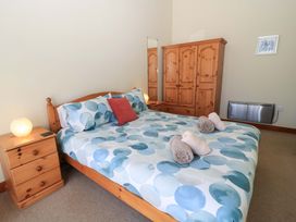 A bedroom with a double bed a wooden wardrobe bedside tables and folded towels on the bed at The Old Stables in Winterborne Stickland