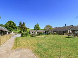 A grass courtyard with picnic tables and low buildings around at The Old Stables in Winterborne Stickland