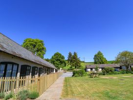 A courtyard with lawns picnic table and cottages with picket fences at The Old Stables in Winterborne Stickland