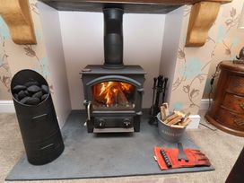 A living room with a wood stove and firewood at Dilston House in Goathland