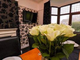 A dining room with a television and a vase of roses at Dilston House in Goathland