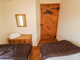 A bedroom with a bed, mirror, and wooden dresser at The Dairy in Penuel near Llanmorlais