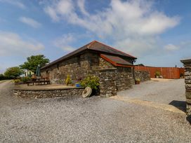 An outdoor view of a stone building with gravel driveway and seating area at The Dairy in Penuel near Llanmorlais