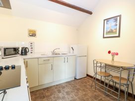 A kitchen with a small dining table and chairs a microwave kettle and fridge at Moonlight Cottage in Coltishall