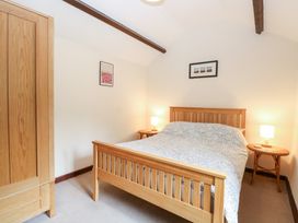 A bedroom with a wooden bed two bedside tables with lamps a wooden wardrobe and two pictures on the wall at Moonlight Cottage in Coltishall