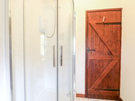 A bathroom with a glass shower enclosure and a wooden door at Moonlight Cottage in Coltishall