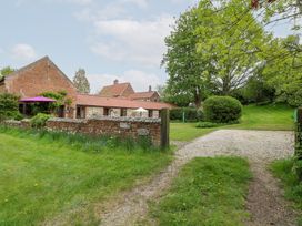 A brick and stone building with a brick wall and a purple umbrella in a grassy yard at Moonlight Cottage in Coltishall