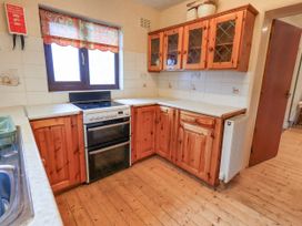 A kitchen with wooden cabinets and a stove at Ghyll Bank House in Staveley near Windermere