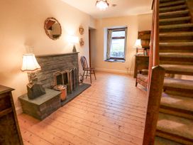 A living room with a fireplace and staircase at Ghyll Bank House Staveley near Windermere