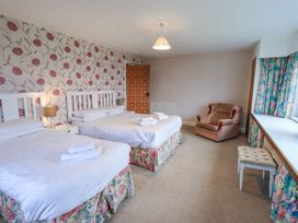 A bedroom with two beds and a chair at Ghyll Bank House in Staveley near Windermere