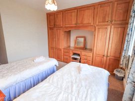 A bedroom with two beds and a wardrobe at Ghyll Bank House in Staveley near Windermere