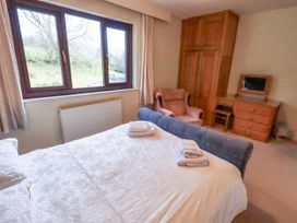 A bedroom with a bed, dresser, and chair at Ghyll Bank House Staveley near Windermere