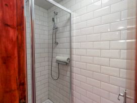 A shower with glass door and tiled wall at Ghyll Bank House Staveley near Windermere