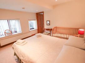 A bedroom with a bed, crib, lamp, and mirror at Ghyll Bank House Staveley near Windermere