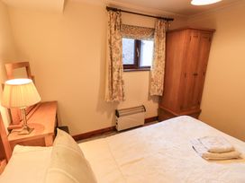 A bedroom with a bed, lamp, wardrobe and window at Ghyll Bank Bungalow Staveley near Windermere