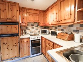 A kitchen with wooden cabinets and appliances at Ghyll Bank Bungalow Staveley near Windermere