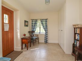 A hallway with a door, window, small table, chair, and bookshelf at Stable Cottage in Cawton near Hovingham