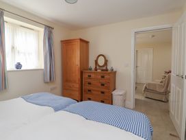 A bedroom with two beds and a wardrobe at Stable Cottage in Cawton near Hovingham