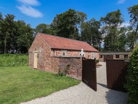 A brick building with a gravel driveway and gate at Stable Cottage in Cawton near Hovingham