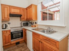A kitchen with wooden cabinets and appliances at Riverside Cottage Llanwrthwl near Rhayader