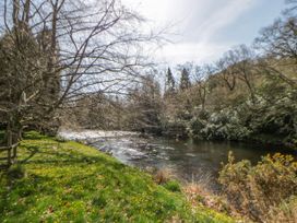 A river with grass and trees at Riverside Cottage in Llanwrthwl near Rhayader