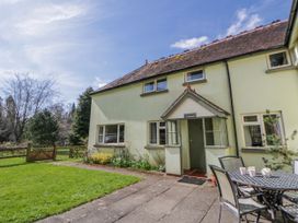 An outdoor area with a house, table, and chairs at Gardener's Cottage in Llanwrthwl near Rhayader