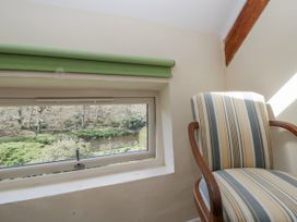 A chair next to a window overlooking a natural view at Gardener's Cottage Llanwrthwl near Rhayader