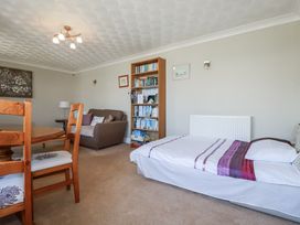 A living room with a table and chairs next to a sofa and bookshelf at Jenny Wren in Tywardreath near Fowey