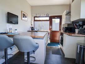 A kitchen with bar stools and appliances at Jenny Wren in Tywardreath near Fowey