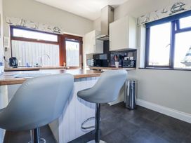 A kitchen with bar stools and appliances at Jenny Wren near Tywardreath Fowey