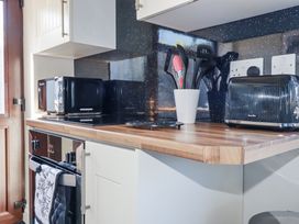 A kitchen with a microwave, toaster, and utensils at Jenny Wren in Tywardreath near Fowey