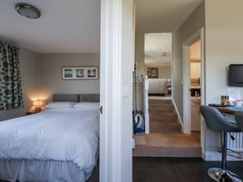 A bedroom with a bed and lamp leading to stairs at Jenny Wren in Tywardreath near Fowey