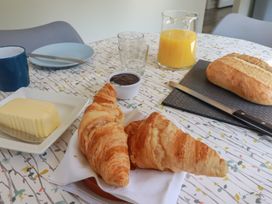 A breakfast setup with croissants, butter, jam, orange juice, and bread loaf at The Station Flat in St Newlyn East near Newquay
