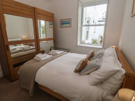 A bedroom with a bed and mirror at Apartment 1 Llewellan St Ives