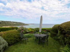 A garden with a table and chairs overlooking the sea at Apartment 1 Llewellan in St Ives