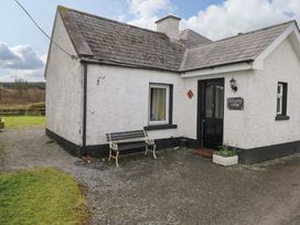 A cottage exterior with a bench and front door at Ballaghboy Cottage in Boyle, County Sligo