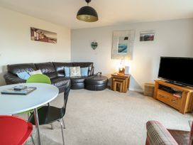 A living room with a sofa and TV at Beach View in Benllech near Red Wharf Bay