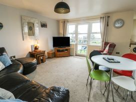 A living room with a television and dining table at Beach View in Benllech near Red Wharf Bay