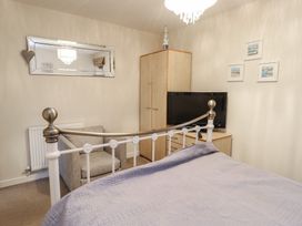 A bedroom with a bed, wardrobe, television and chair at Beach View in Benllech near Red Wharf Bay