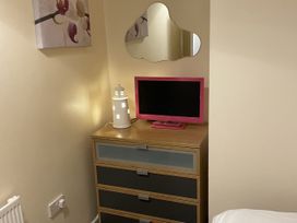 A bedroom with a dresser and television at Beach View Benllech near Red Wharf Bay