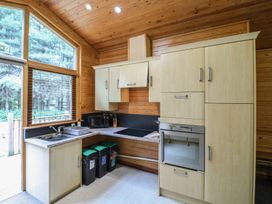 A kitchen with wooden cabinets a sink a microwave an oven and three trash bins at Birch Lodge in Rosliston