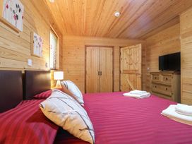 A bedroom with wooden walls and ceiling with a bed covered in red striped bedding at Birch Lodge in Rosliston