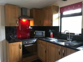A kitchen with wooden cabinets and appliances at Bluebell Lodge in Saltburn-by-the-Sea