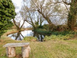 A wooden bench near a small pond surrounded by trees and grass at Violet Lodge in Saltburn-by-the-Sea