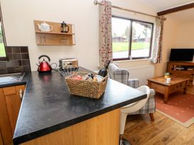A kitchen counter with a basket and appliances next to a living area with chairs a coffee table and a television at Violet Lodge in Saltburn-by-the-Sea